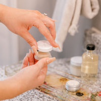 A pressed flower display tray is used as a dish to hold powder room beauty supplies while a woman prepares for the day.