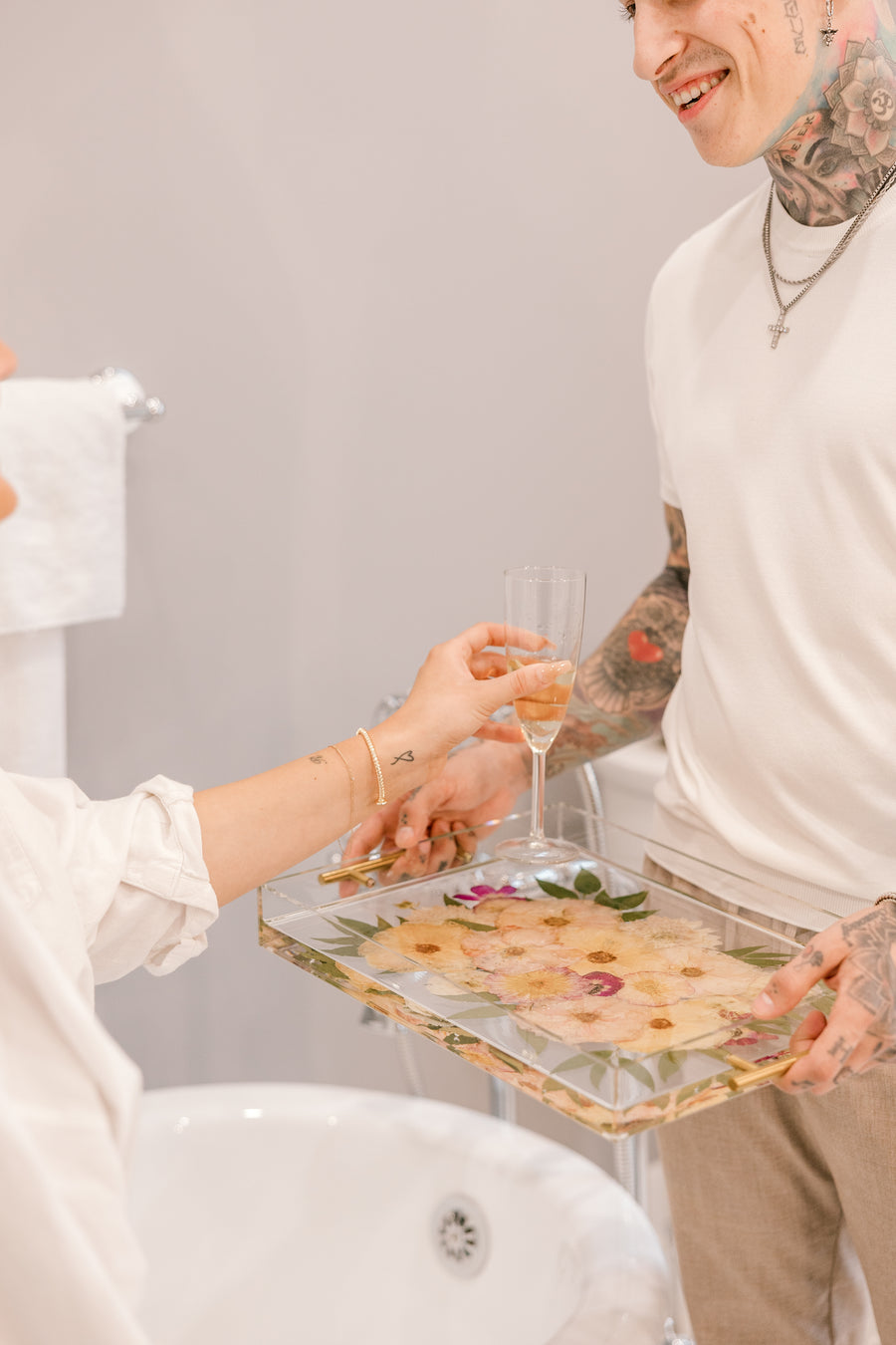 A pressed flower serving tray is used to serve a glass of champagne to a woman as she refreshes from the day. 