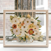 Pressed flowers and pressed florals in a natural wood float frame featuring pressed roses, pressed dahlias, pressed ranunculus, and pressed greenery. 