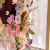 The texture of these beautifully bright pressed flowers are displayed in a gold wood frame and showcased on an angle for a unique bouquet preservation design. 