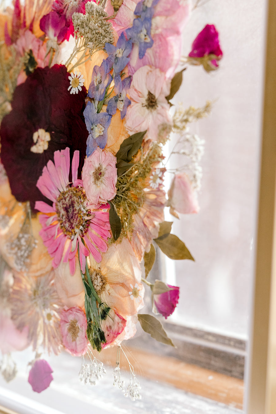 The texture of these beautifully bright pressed flowers are displayed in a gold wood frame and showcased on an angle for a unique bouquet preservation design. 