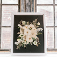 Pressed White florals against a black background showcased in a window sill. 