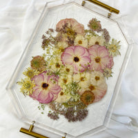 A spring-toned wedding bouquet preserved in a resin serving tray with gold handles.