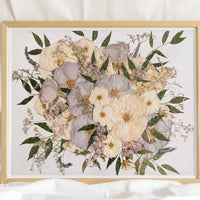 A pressed flower bouquet preserved in a glass frame with a gold wood surround, made by Element Preservation (Element Design Co.)