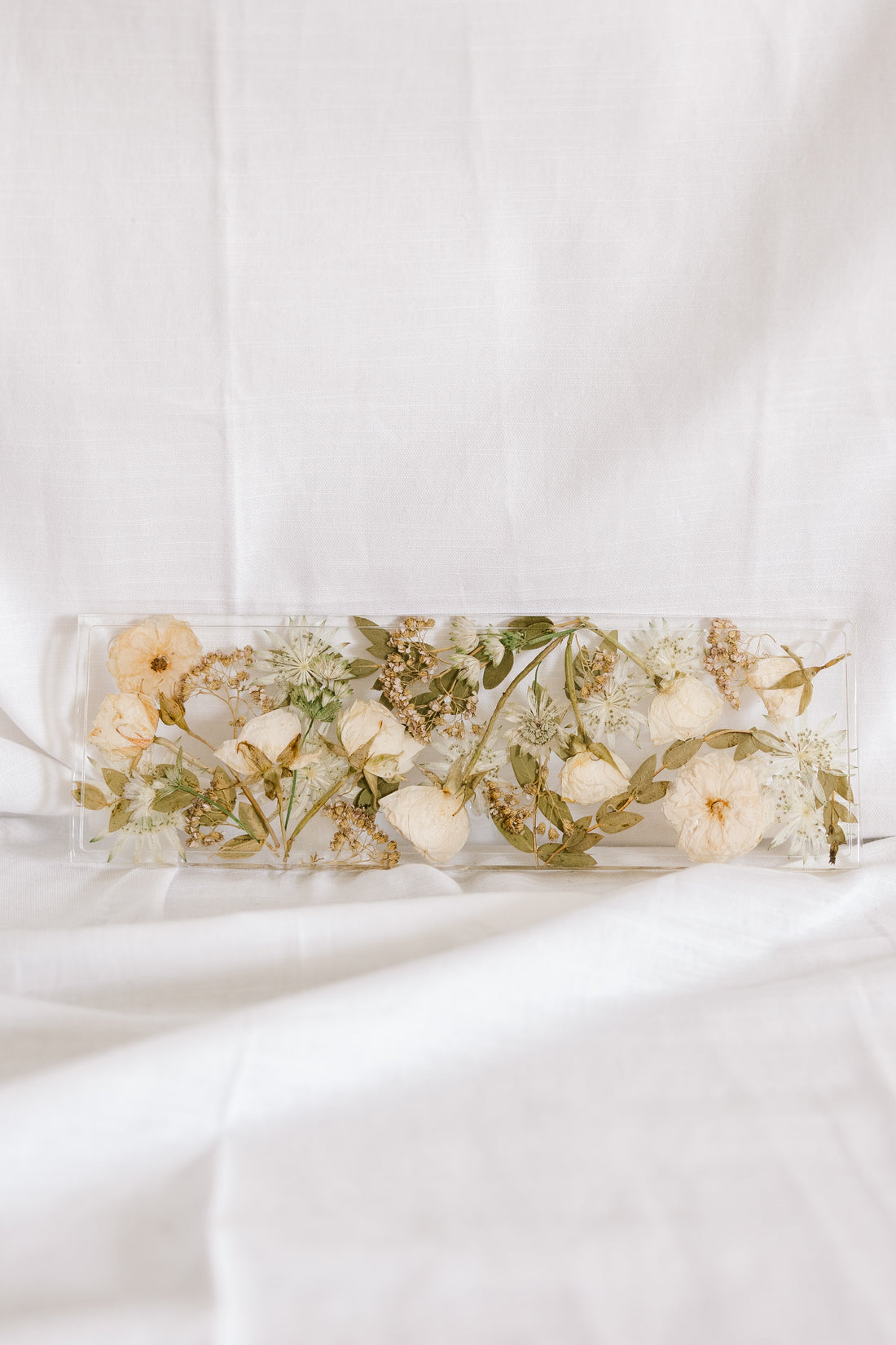 White and green wedding flowers fill a 13x4 inch display tray made out of resin by the Pressed Bouquet Shop.