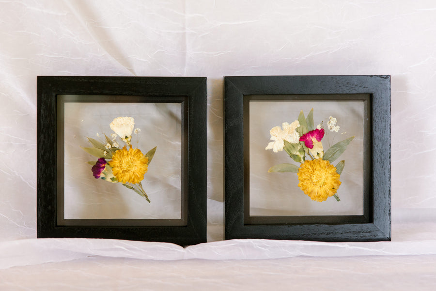 Two boutonnieres pressed and preserved in 6x6" black wood frames.