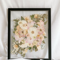 A wedding bouquet pressed and framed inside a black floating frame with a subtle wedding date detail added to the bottom right corner. 