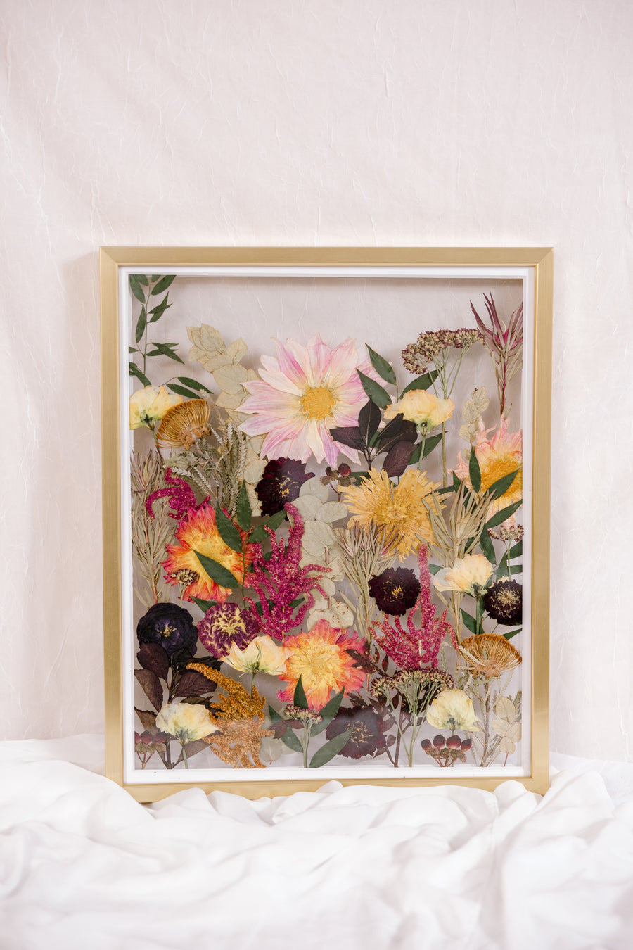 Pressed flowers are displayed as if they were growing from the ground in this gold wood floating frame.