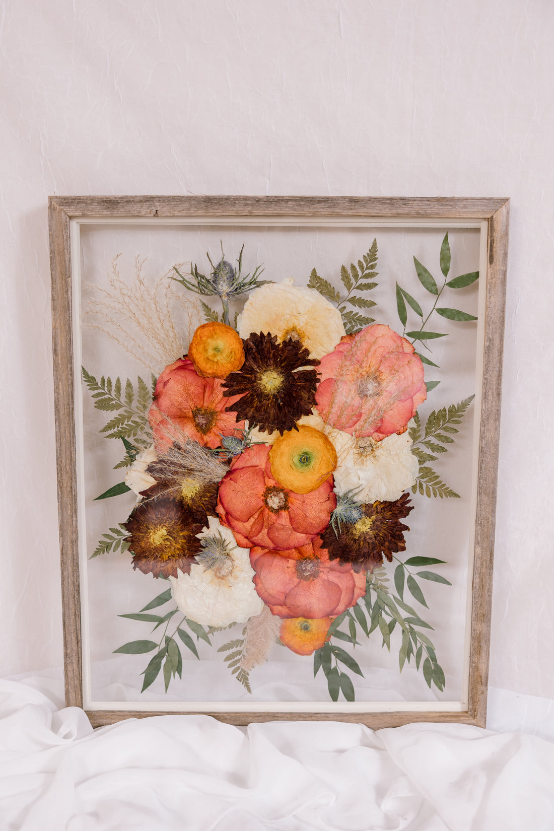 A vibrant pressed flower arrangement inside a barn wood frame. 