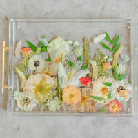 Pressed flower resin serving tray with gold handles in a field style design.