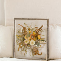 A fall pressed bouquet sitting against pillows on a bed.  