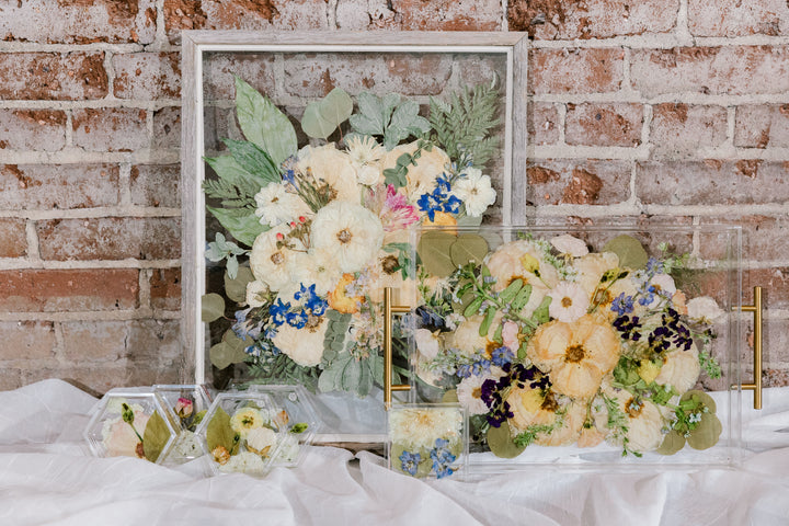 The Works bouquet preservation bundle with a pressed flower frame, a preserved flower serving tray, resin flower coasters, and a resin flower ring dish created by Element Preservation, previously known as Pressed Bouquet Shop. 