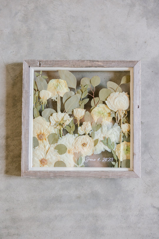 A 10x10 white flower frame with a wedding date by Element Preservation, previously known as Pressed Bouquet Shop. 