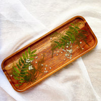 Pressed greenery and baby's breath on a wooden resin tray for home decor
