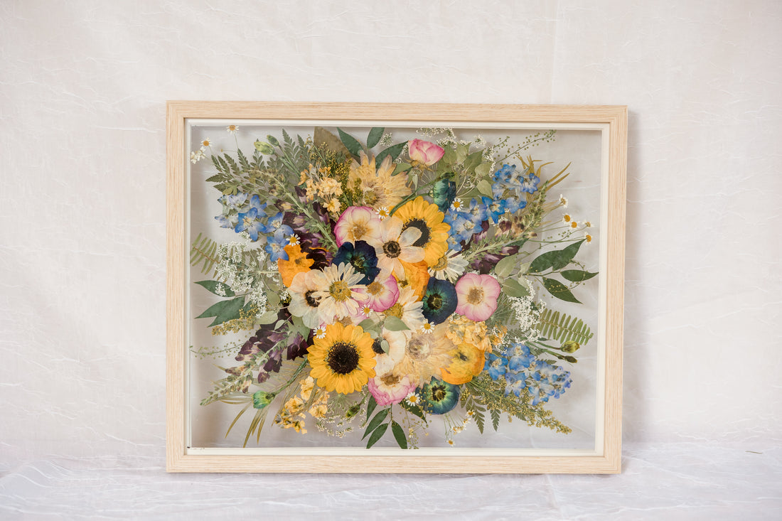A wildflower wedding bouquet pressed and framed inside a natural wood frame.