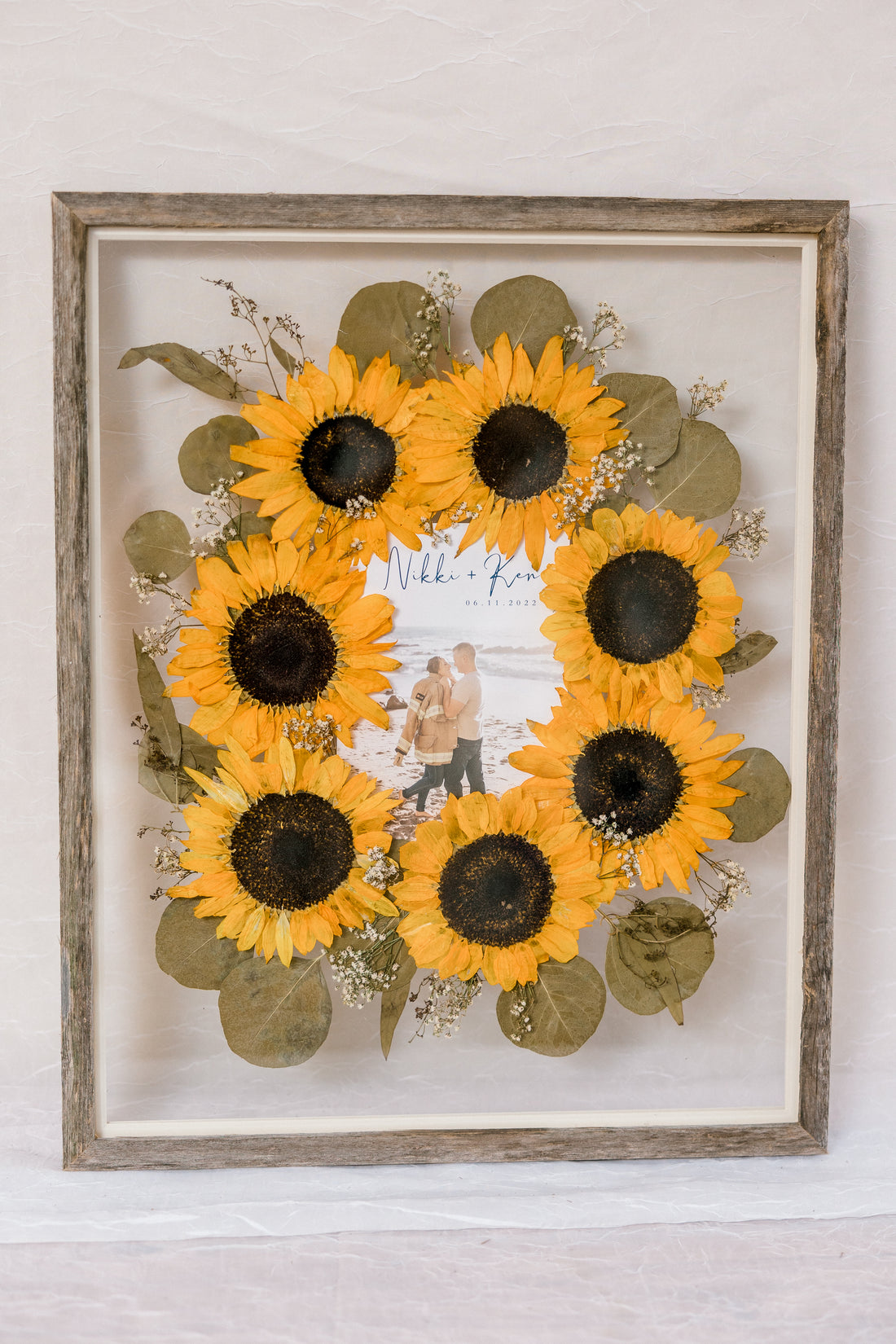 Barn wood frame with pressed sunflowers in burst style design with invitation