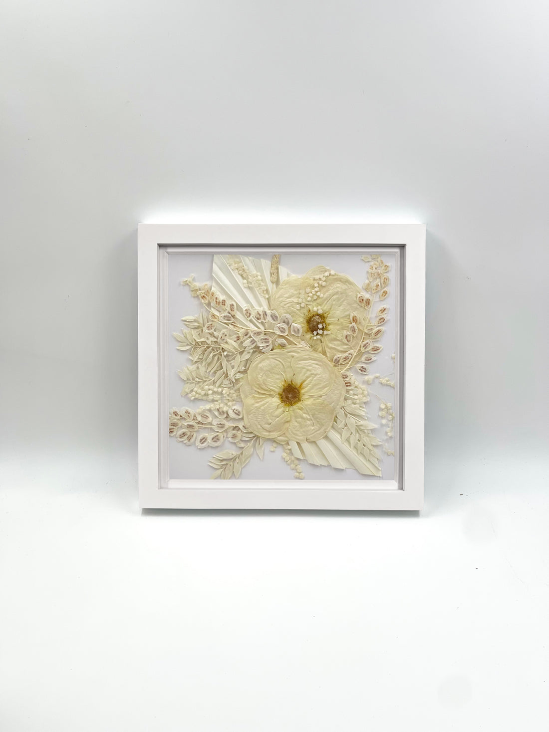 An all-white bridesmaid bouquet preserved and styled inside a white 10x10" frame on a white background